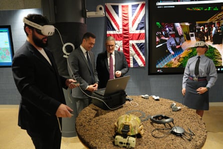 Keir Starmer and a Palantir employee look at a laptop as two people either side of them wear VR headsets