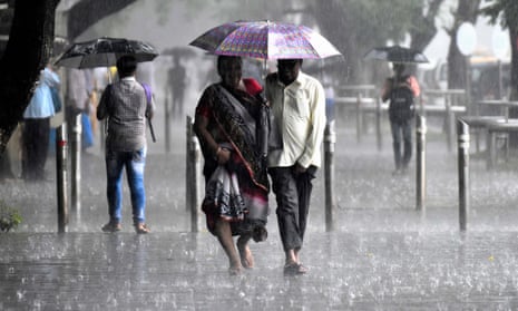Commuters cover themselves under umbrellas after a sudden rain shower at St Xavier’s College in Mumbai, India. 