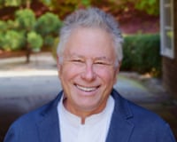 Composer Alan Menken smiling outdoors in casual business attire
