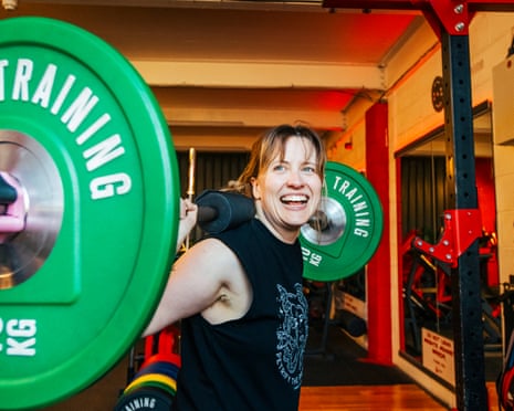 Laura Evans lifts a dumbbell behind her shoulders, with a fierce grin
