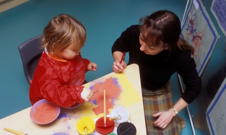 A teacher and a child in a nursery, painting.