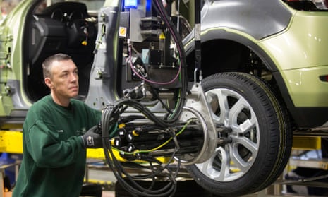A worker uses a robotic arm to fix an alloy wheel to the hub of a Range Rover Evoque SUV