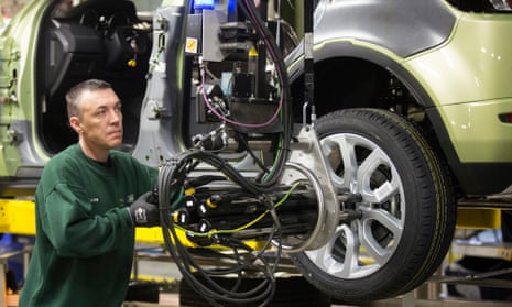 An employee uses a robotic arm to fix an alloy wheel to the hub of a Range Rover Evoque.