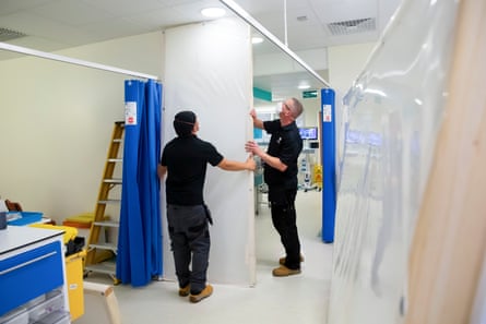 Construction workers erect a partition wall in critical care.