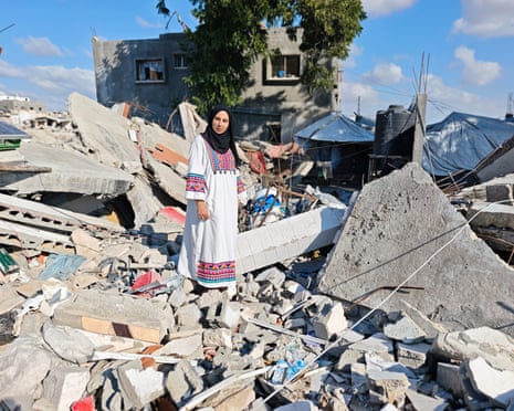 Alaa Hessi stands amid the rubble of her home, destroyed by an Israeli strike