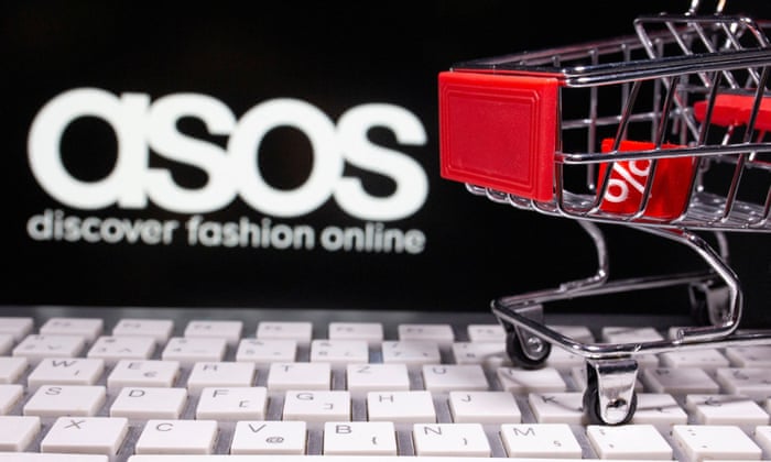 A keyboard and a shopping cart are seen in front of a displayed ASOS logo.