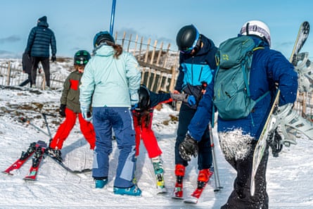 Adults helping child to feet on skis