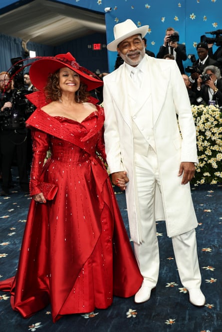 Debbie Allen in a red silk ballgown and hat holding hands with Norm Nixon in an all-white suit and fedora