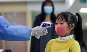 A Kenyan health worker screens a young passenger from China at Jomo Kenyatta International airport in class=