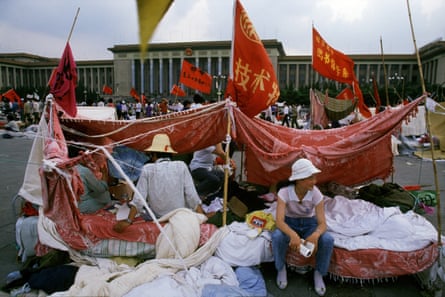 Student sit surrounded by red flags with imposing buildings in the background