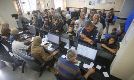 People wait in line in front of several people sat at computer screens