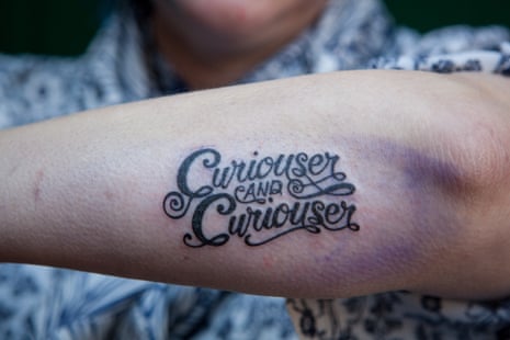 A forearm tattoo reading "Curiouser and curiouser"