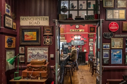 The interior of a pub with wood-panelled and orange coloured walls, wood floors and seating and train memorabilia on the walls