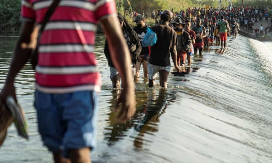 Migrants seeking asylum in the US walk in the Rio Grande River near the International Bridge between Mexico and the US, as they wait to be processed, in Ciudad Acuña, Mexico, on Thursday.