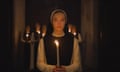 a nun holding a candle with other nuns behind her