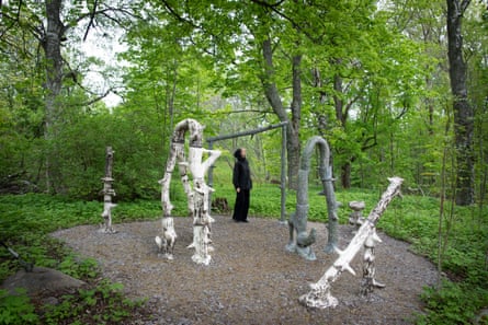 A woman in black admiring sculptures in woods