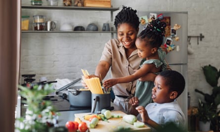 Mother, Daughter and Son Preparing Spaghetti and Vegetables for Lunch over a Cutting Board