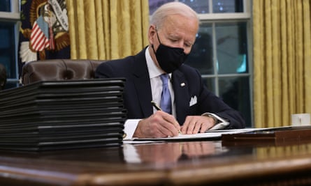 Joe Biden prepares to sign a series of executive orders at the Resolute desk.