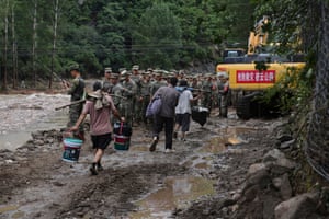 Residents in Miyun district, on the outskirts of Beijing, walk with soldiers as the prepare to rescue people trapped after a a road was damaged by heavy rains and flooding.