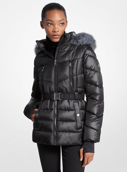 Un modelo con una chaqueta acolchada con cinturón y ribete de piel sintética de Michael Kors.