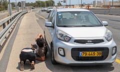 People lie on the ground next to a car on the hard shoulder of a road