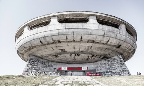 The Buzludzha monument; which looks like a concrete flying saucer balanced atop a grey concrete stand covered in Cyrillic, with additional graffiti.