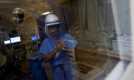 A nurse wearing a face shield sanitizes her hands inside the intensive care unit.