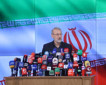 Larijani speaking at a lectern with many microphones