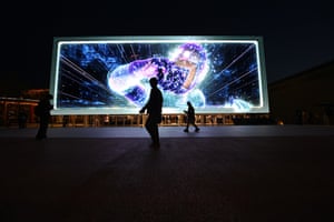 A visitor silhouetted as they walk past a 3D screen
