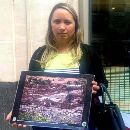 Monica dos Santos holds a photograph showing destruction caused by the dam collapse