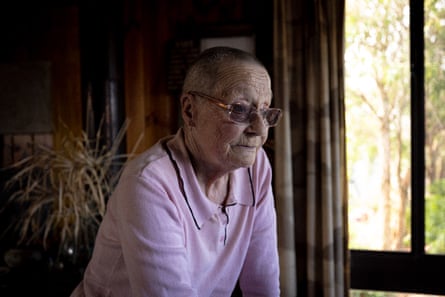 Deb McDonald wearing a pink polo top, glasses with her head shaven looking out her window