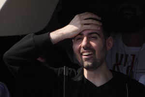 Man smiling, holding a hand to his forehead