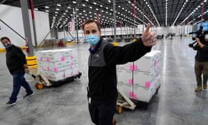 A worker gives a thumbs up while transporting boxes containing the Moderna Covid-19 vaccine
