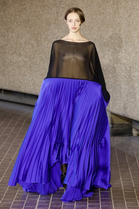 A woman wearing a dress with a full blue skirt and a sheer black top.