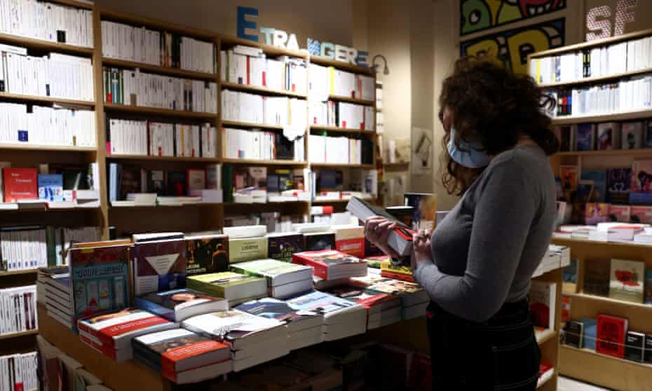 A bookseller arranges books in an independent shop in Paris.