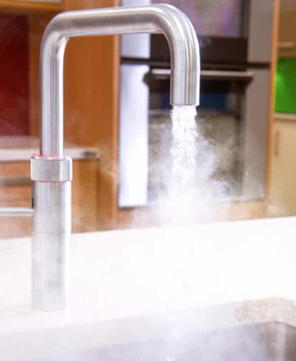 An instant hot water tap running steaming water into a kitchen sink.