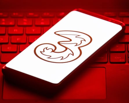 the Three logo on a smartphone with a keyboard in the red tinted background