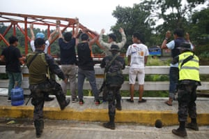 Male residents are frisked by police at a checkpoint as they leave Marawi