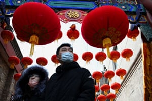 People walk under traditional lanterns a day before the start of the Lunar New Year in Beijing.