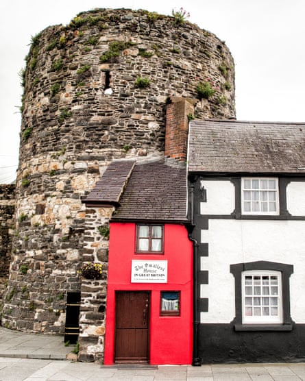 A tiny red house stands next between the walls of Conwy Castle and a little black and white cottage.