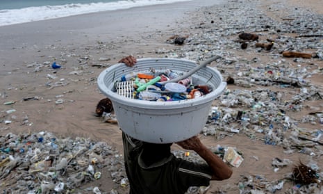 A woman collects recyclable plastics washed up on the beach in Bali, Indonesia.