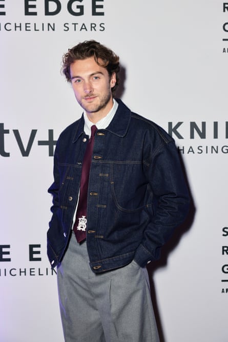 Man poses for cameras on event's red carpet.