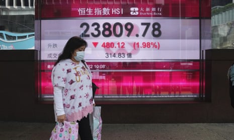 A woman walks past a bank's electronic board showing the Hong Kong share index in Hong Kong on Thursday.