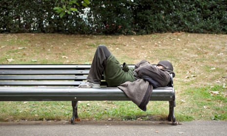 A homeless man sleeping on a bench in central London. 