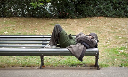 A homeless man sleeping on a bench in central London