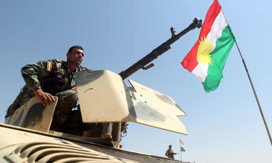 A flag of the autonomous Kurdistan region flies next to an Iraqi Kurdish Peshmerga fighter as he takes position to monitor the area from their front line post in Bashiqa, a town 13 kilometres north-east of Mosul on August 16, 2014. Kurdish troops backed by US warplanes launched a bid to recapture Mosul dam, Iraq’s largest, from Islamic State jihadists, a senior Kurdish military official said. AFP PHOTO/AHMAD AL-RUBAYEAHMAD AL-RUBAYE/AFP/Getty Images