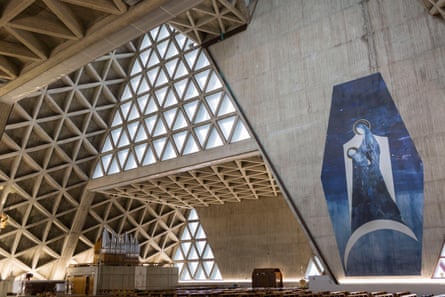 The interior of a brutalist church with repeated triangular shapes in the ceiling.