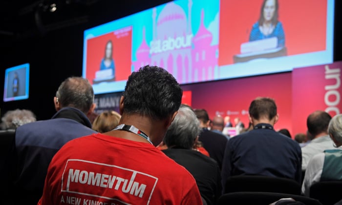 A member of the audience wearing ‘Momentum’ political campaigning organisation T-shirt listens to speeches at the Labour conference.