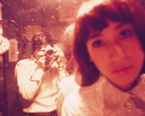 Daido Moriyama and Fuji Keiko take mirror selfies with a camera, one holding it and one in soft focus.