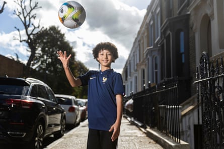 Adam Tounsi standing in a residential street wearing the France kit and throwing a football in the air